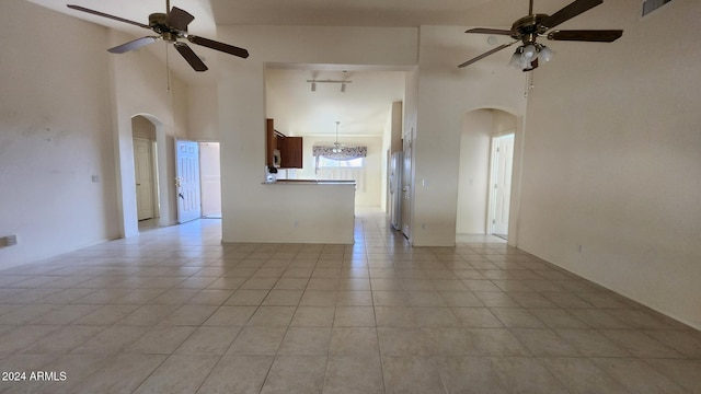 spare room featuring light tile patterned floors, a towering ceiling, and ceiling fan