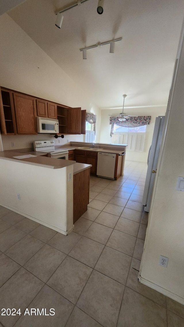 kitchen featuring white appliances, rail lighting, hanging light fixtures, light tile patterned floors, and kitchen peninsula