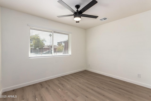 empty room with baseboards, visible vents, ceiling fan, and wood finished floors