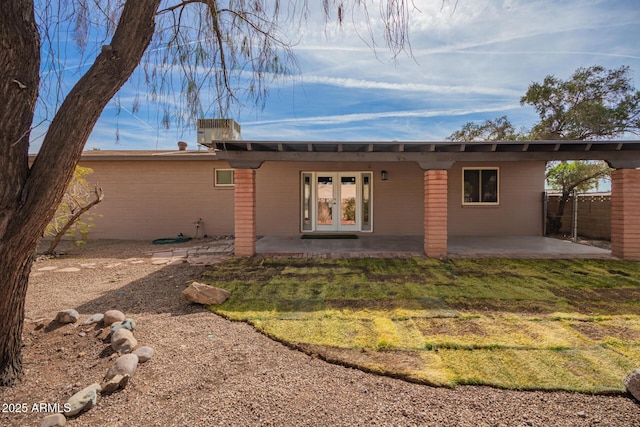 rear view of property with central air condition unit, fence, french doors, a lawn, and a patio area