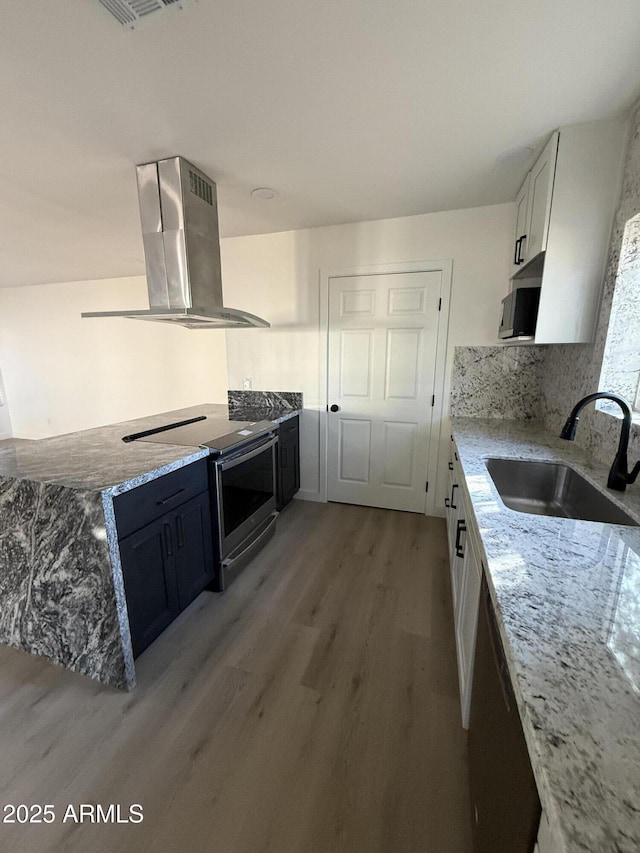 kitchen with light stone counters, stainless steel appliances, a sink, white cabinetry, and island exhaust hood