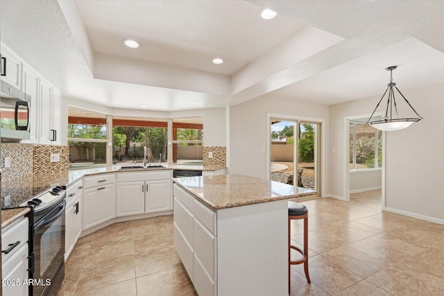 kitchen featuring black range with electric cooktop, a center island, stainless steel microwave, tasteful backsplash, and a sink