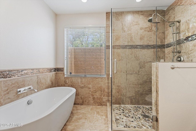 full bath featuring a freestanding tub, tile walls, a shower stall, a wainscoted wall, and recessed lighting