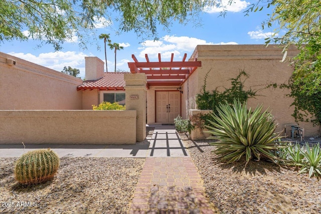 view of front of home featuring stucco siding, a tiled roof, and fence