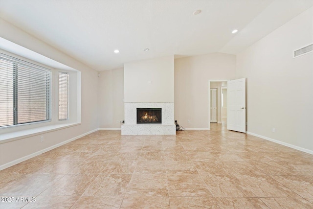 unfurnished living room featuring visible vents, a premium fireplace, recessed lighting, baseboards, and vaulted ceiling