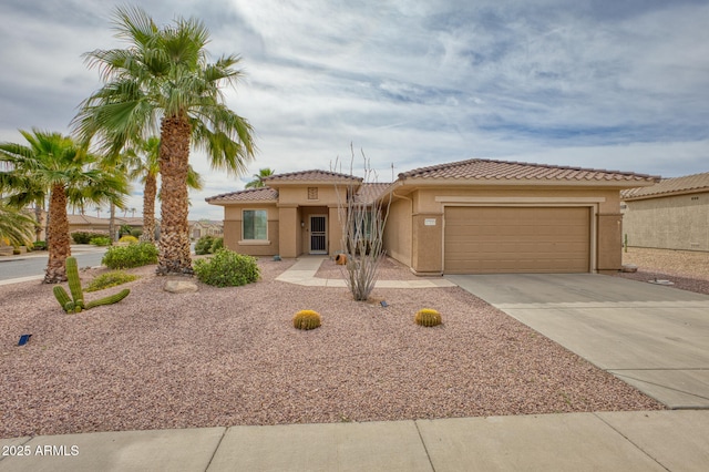 mediterranean / spanish-style house with concrete driveway, an attached garage, a tiled roof, and stucco siding