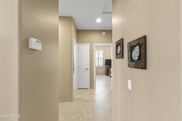 hall featuring light tile patterned floors and baseboards