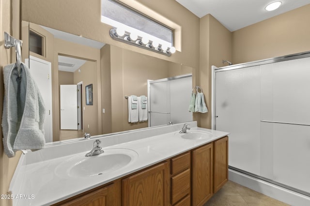 full bathroom featuring double vanity, tile patterned flooring, a shower stall, and a sink