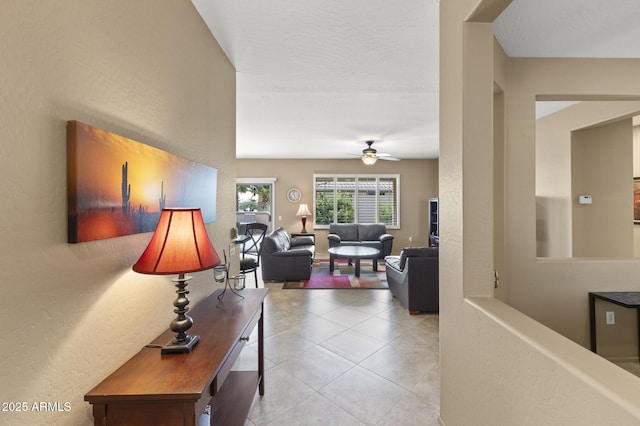 living area with light tile patterned floors and ceiling fan