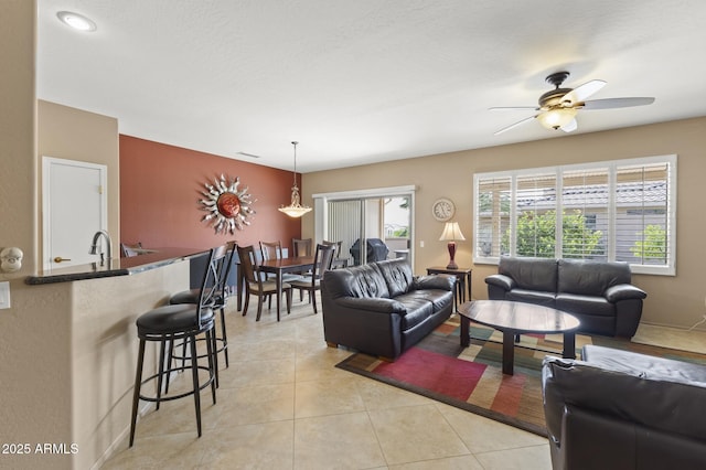 living room featuring light tile patterned floors, visible vents, and a ceiling fan