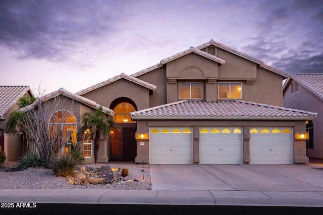 view of front of home featuring driveway, a tiled roof, a garage, and stucco siding