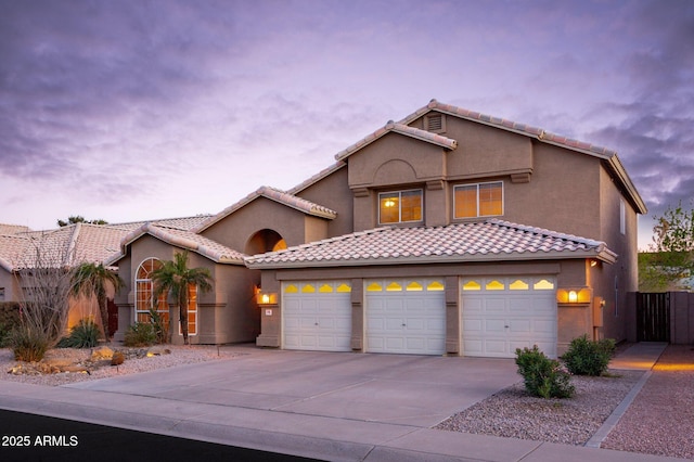 view of front of home with stucco siding, concrete driveway, fence, a garage, and a tiled roof