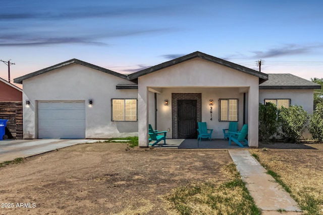3614 W Granada Rd, Phoenix, AZ 85009 - view of front of house featuring a porch, a garage, stucco siding, and driveway