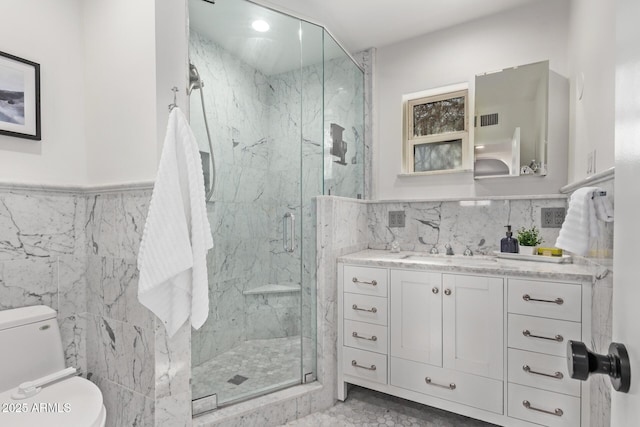 bathroom featuring vanity, a shower with shower door, tile walls, and toilet