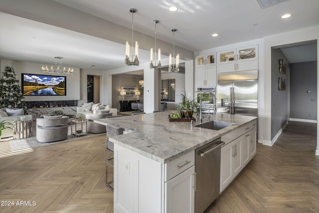 kitchen featuring light parquet flooring, a kitchen island with sink, and white cabinets