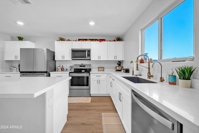 kitchen with appliances with stainless steel finishes, light hardwood / wood-style floors, white cabinetry, and sink