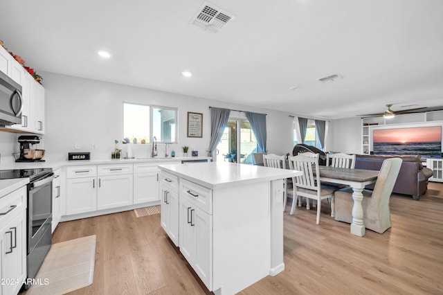 kitchen featuring appliances with stainless steel finishes, white cabinetry, light hardwood / wood-style flooring, and plenty of natural light