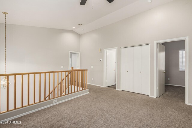 unfurnished bedroom with high vaulted ceiling, ceiling fan, a closet, and carpet