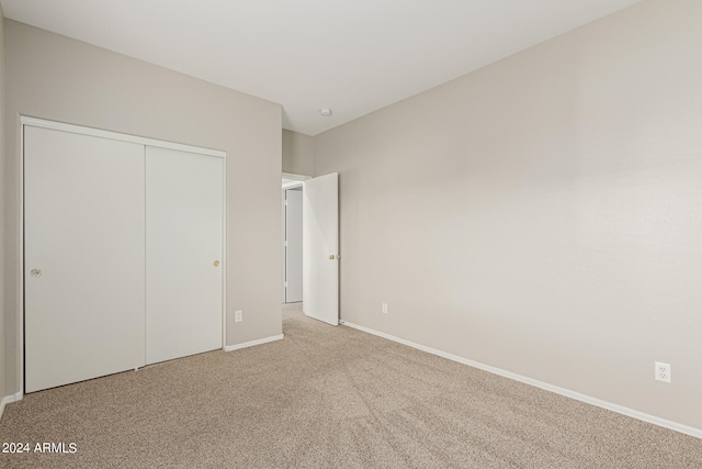 unfurnished bedroom featuring a closet and light carpet