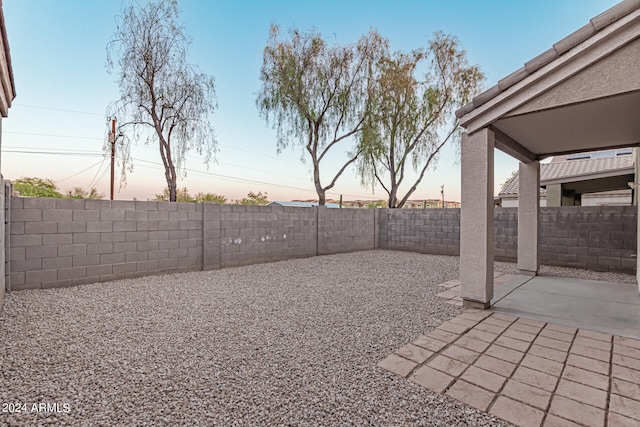 yard at dusk featuring a patio