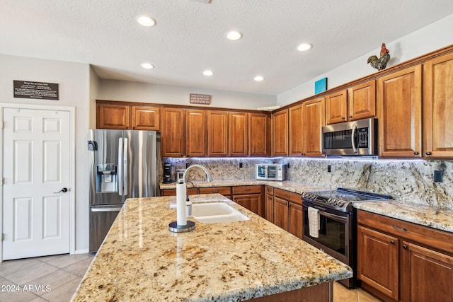 kitchen with a kitchen island with sink, stainless steel appliances, sink, and light stone counters