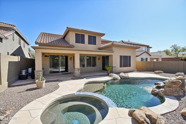 rear view of house featuring pool water feature, a swimming pool with hot tub, and a patio area