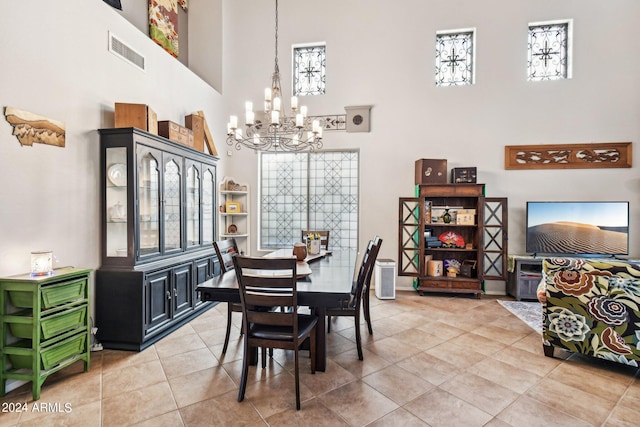 dining space featuring a towering ceiling, tile patterned floors, and a notable chandelier