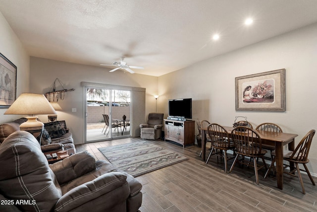 living room featuring wood-type flooring, a textured ceiling, and ceiling fan