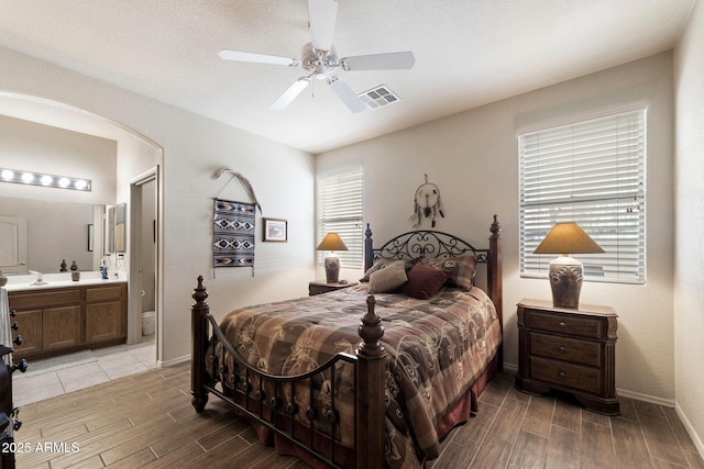 bedroom with ceiling fan, ensuite bath, and sink