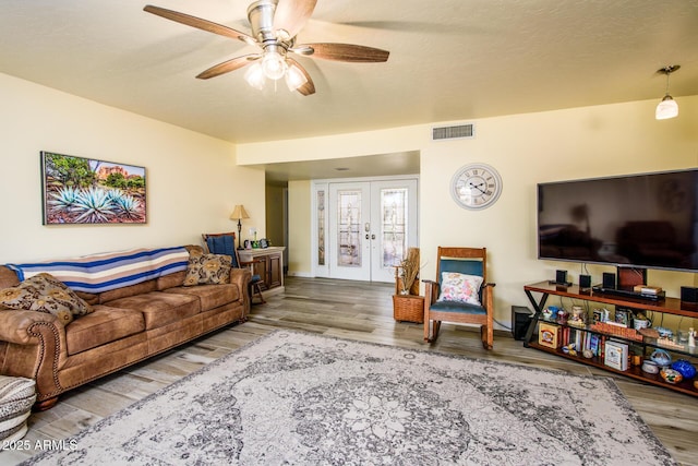 living area featuring wood finished floors, visible vents, ceiling fan, french doors, and a textured ceiling