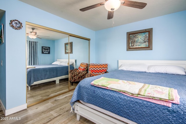 bedroom with a closet, baseboards, a ceiling fan, and wood finished floors