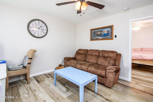 living room featuring visible vents, light wood-style floors, baseboards, and ceiling fan