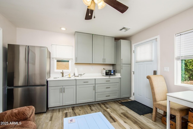 kitchen with light wood-type flooring, visible vents, gray cabinets, freestanding refrigerator, and white microwave