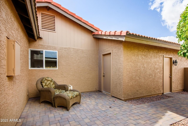 rear view of property featuring a patio area, stucco siding, and a tile roof