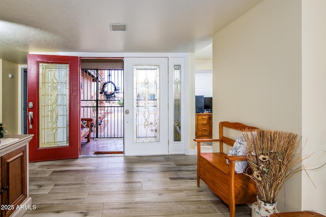 entryway with visible vents, a textured ceiling, and wood finished floors