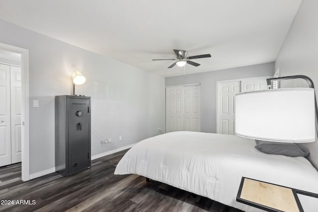 bedroom featuring ceiling fan, dark hardwood / wood-style flooring, and two closets