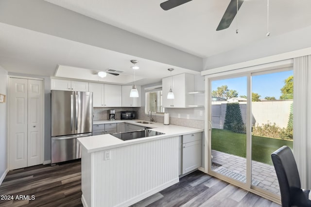 kitchen featuring stainless steel refrigerator, white cabinetry, dark hardwood / wood-style floors, kitchen peninsula, and black electric stovetop