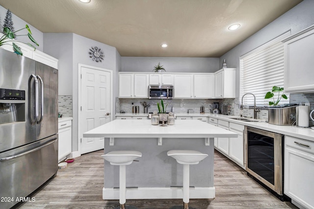 kitchen with beverage cooler, stainless steel appliances, decorative backsplash, and a kitchen island