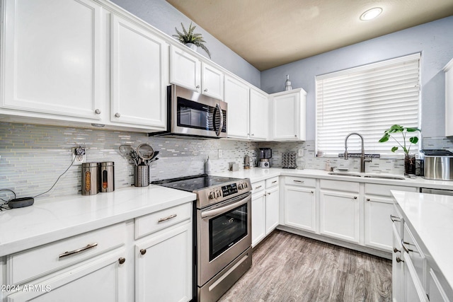 kitchen with white cabinets, stainless steel appliances, light wood-type flooring, and sink