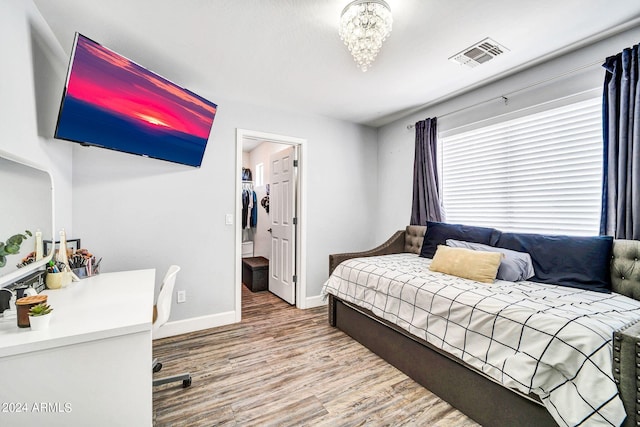 bedroom with an inviting chandelier, a walk in closet, and hardwood / wood-style flooring