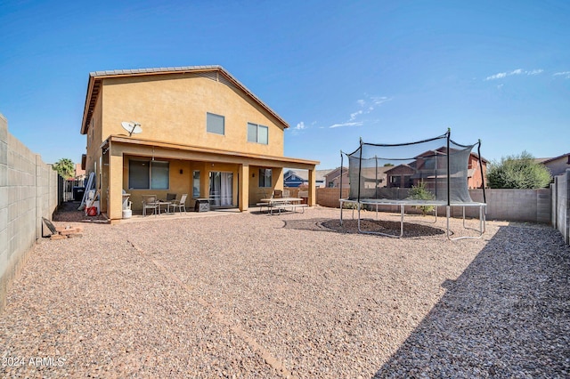 back of house with a trampoline and a patio