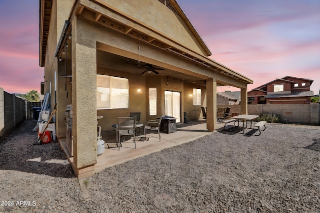 back house at dusk featuring a patio and ceiling fan