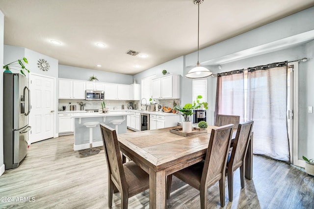 dining room with wine cooler, light wood-type flooring, and sink