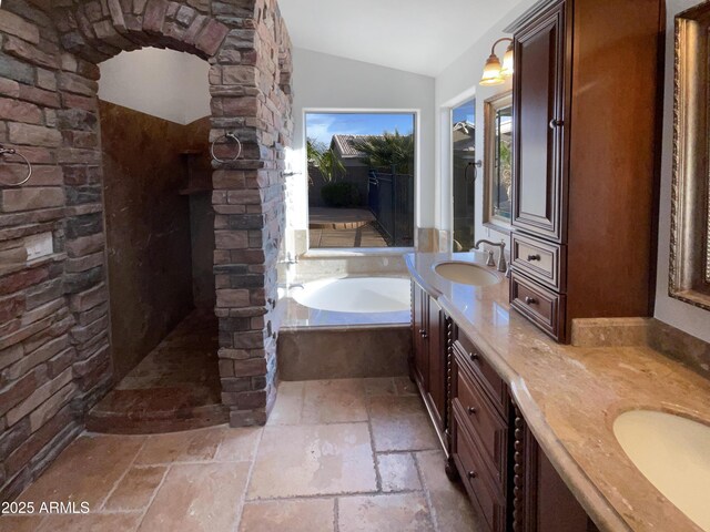 bathroom with vanity, a bath, and lofted ceiling