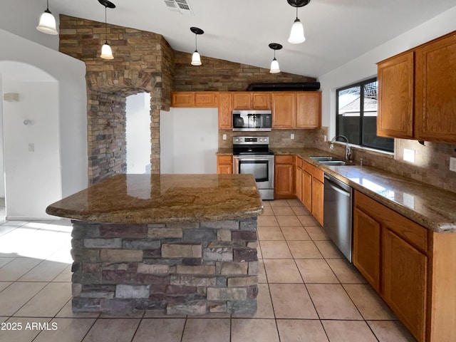 kitchen featuring sink, backsplash, vaulted ceiling, decorative light fixtures, and appliances with stainless steel finishes