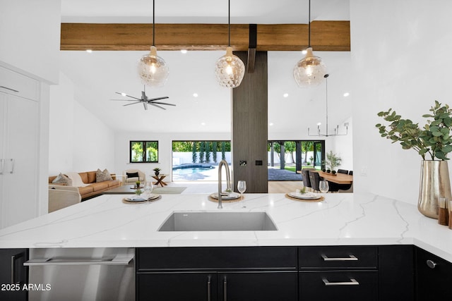 kitchen with beamed ceiling, open floor plan, a sink, and dark cabinetry