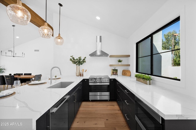 kitchen featuring stainless steel appliances, dark cabinetry, and wall chimney range hood