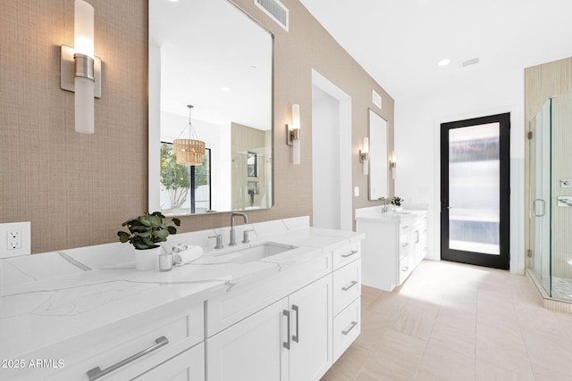 full bath with a stall shower, two vanities, a sink, and visible vents