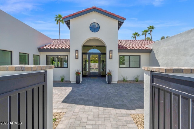 exterior space featuring french doors, a tiled roof, and stucco siding