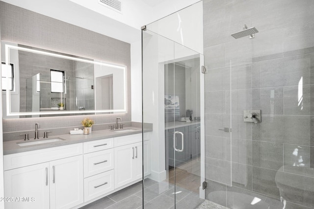 bathroom with a sink, visible vents, a shower stall, and double vanity